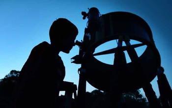 person looking through a telescope at the sky